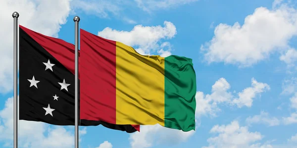 Bandera de Papúa Nueva Guinea y Guinea ondeando en el viento contra el cielo azul nublado blanco juntos. Concepto diplomático, relaciones internacionales . — Foto de Stock