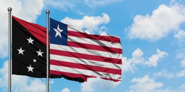 Papua Yeni Gine ve Liberya bayrağı birlikte beyaz bulutlu mavi gökyüzüne karşı rüzgarda sallayarak. Diplomasi kavramı, uluslararası ilişkiler.