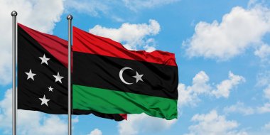 Papua Yeni Gine ve Libya bayrağı birlikte beyaz bulutlu mavi gökyüzüne karşı rüzgarsal sallayarak. Diplomasi kavramı, uluslararası ilişkiler.
