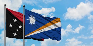 Papua Yeni Gine ve Marshall Adaları bayrağı birlikte beyaz bulutlu mavi gökyüzüne karşı rüzgarda sallayarak. Diplomasi kavramı, uluslararası ilişkiler.