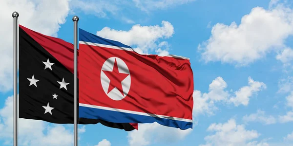 Papua-Nova Guiné e bandeira da Coreia do Norte agitando no vento contra o céu azul nublado branco juntos. Conceito de diplomacia, relações internacionais . — Fotografia de Stock