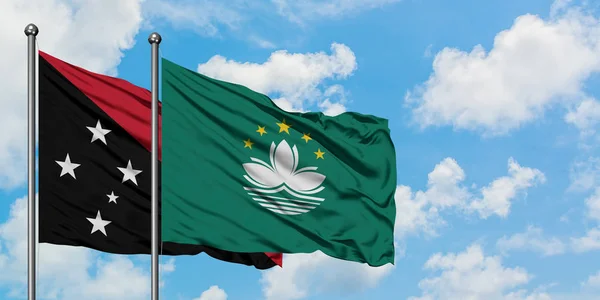 Bandera de Papúa Nueva Guinea y Macao ondeando en el viento contra el cielo azul nublado blanco juntos. Concepto diplomático, relaciones internacionales . — Foto de Stock