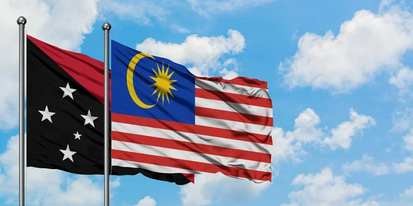 Vlajka Papuy-Nové Guiney a Malajsie se ve větru rozvlní proti bílé oblačné obloze. Diplomacie, mezinárodní vztahy. — Stock fotografie