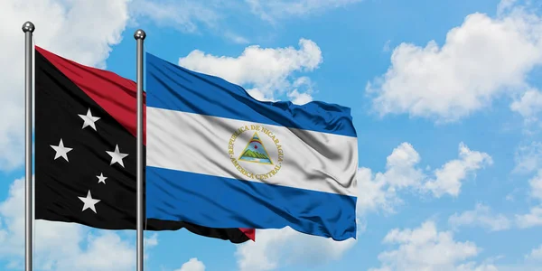 Papua-Nová Guinea a Nikaragujská vlajka mávali ve větru proti bíle zatažené modré obloze. Diplomacie, mezinárodní vztahy. — Stock fotografie