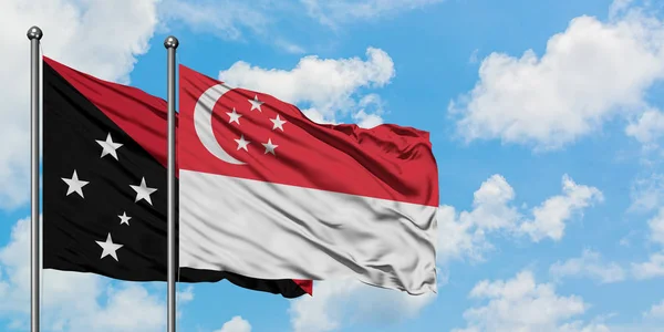 Papua Nova Guiné e Singapura acenando com o vento contra o céu azul nublado branco juntos. Conceito de diplomacia, relações internacionais . — Fotografia de Stock
