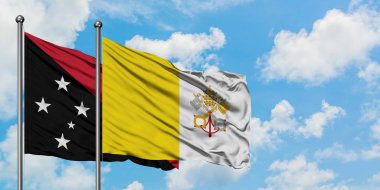 Papua Yeni Gine ve Vatikan bayrağı birlikte beyaz bulutlu mavi gökyüzüne karşı rüzgarda sallayarak. Diplomasi kavramı, uluslararası ilişkiler.