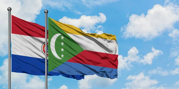 Bandera de Paraguay y Comoras ondeando en el viento contra el cielo azul nublado blanco juntos. Concepto diplomático, relaciones internacionales . — Foto de Stock