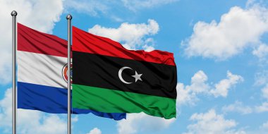 Paraguay ve Libya bayrağı birlikte beyaz bulutlu mavi gökyüzüne karşı rüzgarsal sallayarak. Diplomasi kavramı, uluslararası ilişkiler.