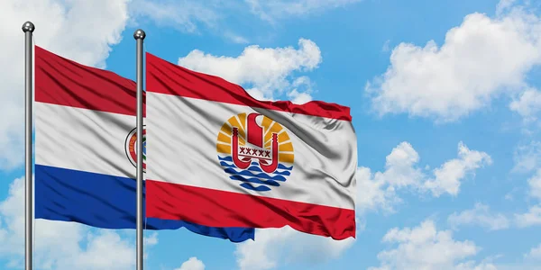 Paragwaj i Polinezja Francuska flaga machając w wiatr przed białym zachmurzone błękitne niebo razem. Koncepcja dyplomacji, stosunki międzynarodowe. — Zdjęcie stockowe