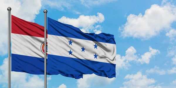 Парагвай и Гондурас вместе машут на ветру против белого облачно-синего неба. Концепция дипломатии, международные отношения . — стоковое фото