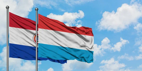 Paragwaj i Luksemburg flaga machając w wiatr przed białym zachmurzone błękitne niebo razem. Koncepcja dyplomacji, stosunki międzynarodowe. — Zdjęcie stockowe