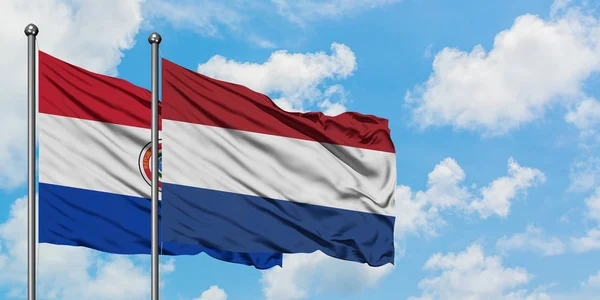 Paragwaj i flaga Holandii machając w wiatr przed białym zachmurzone błękitne niebo razem. Koncepcja dyplomacji, stosunki międzynarodowe. — Zdjęcie stockowe