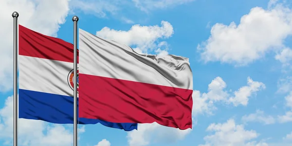 Парагвай і польський прапор розмахував вітром проти білого хмарного синього неба разом. Концепція дипломатії, міжнародні відносини. — стокове фото