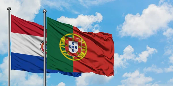 Bandera de Paraguay y Portugal ondeando en el viento contra el cielo azul nublado blanco juntos. Concepto diplomático, relaciones internacionales . — Foto de Stock