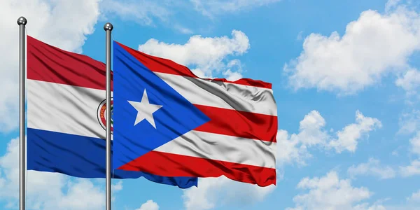 Paraguay und Puerto Rico schwenken gemeinsam die Flagge im Wind vor dem wolkenverhangenen blauen Himmel. Diplomatie-Konzept, internationale Beziehungen. — Stockfoto