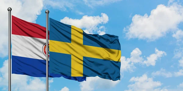 Paraguay a švédská vlajka mávali ve větru proti bíle zatažené modré obloze. Diplomacie, mezinárodní vztahy. — Stock fotografie