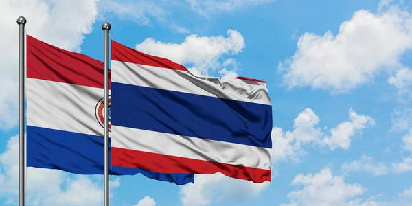 巴拉圭和泰国国旗在风中飘扬，与白云蓝天相一起。外交概念、国际关系. — 图库照片