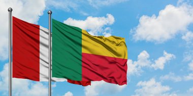 Peru ve Benin bayrağı birlikte beyaz bulutlu mavi gökyüzüne karşı rüzgarda sallayarak. Diplomasi kavramı, uluslararası ilişkiler.