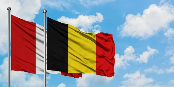 Bandera de Perú y Bélgica ondeando en el viento contra el cielo azul nublado blanco juntos. Concepto diplomático, relaciones internacionales . — Foto de Stock