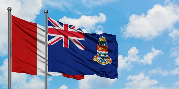 Peru en Caymaneilanden vlag zwaaien in de wind tegen witte bewolkte blauwe hemel samen. Diplomatie concept, internationale betrekkingen. — Stockfoto