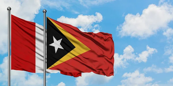 Bandera de Perú y Timor Oriental ondeando en el viento contra el cielo azul nublado blanco juntos. Concepto diplomático, relaciones internacionales . —  Fotos de Stock