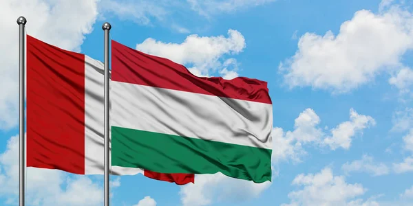 Bandera de Perú y Hungría ondeando en el viento contra el cielo azul nublado blanco juntos. Concepto diplomático, relaciones internacionales . — Foto de Stock