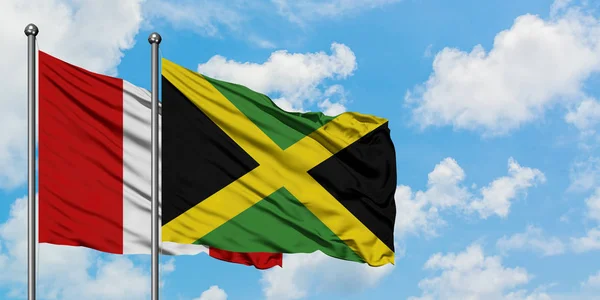 Bandera de Perú y Jamaica ondeando en el viento contra el cielo azul nublado blanco juntos. Concepto diplomático, relaciones internacionales . — Foto de Stock