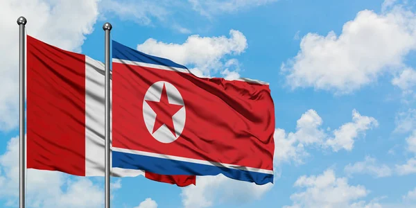 Bandera de Perú y Corea del Norte ondeando en el viento contra el cielo azul nublado blanco juntos. Concepto diplomático, relaciones internacionales . — Foto de Stock