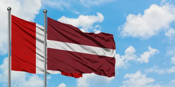 Drapeau du Pérou et de la Lettonie agitant dans le vent contre ciel bleu nuageux blanc ensemble. Concept de diplomatie, relations internationales . — Photo