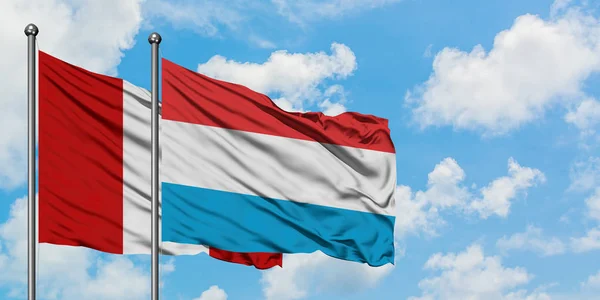 Peru i Luksemburg flagi machając w wiatr przed białym zachmurzone błękitne niebo razem. Koncepcja dyplomacji, stosunki międzynarodowe. — Zdjęcie stockowe