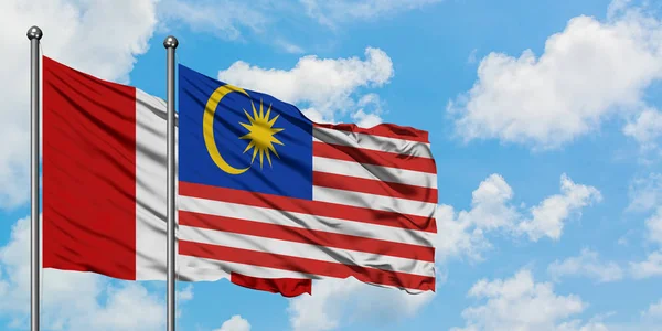 Peruánská a Malajsijská vlajka mávali ve větru proti bíle zatažené modré obloze. Diplomacie, mezinárodní vztahy. — Stock fotografie