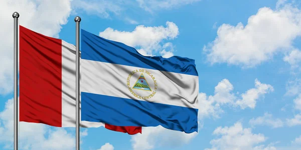 Bandera de Perú y Nicaragua ondeando en el viento contra el cielo azul nublado blanco juntos. Concepto diplomático, relaciones internacionales . — Foto de Stock