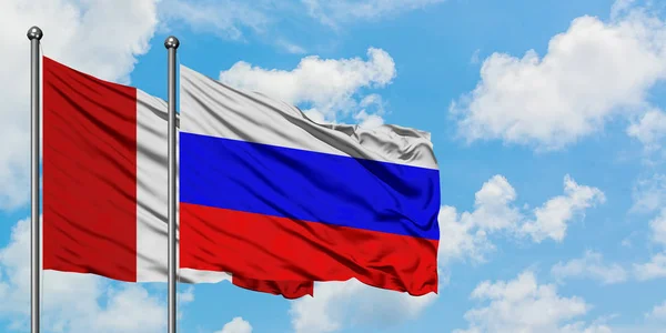 Peru und Russland schwenken gemeinsam die Flagge im Wind gegen den wolkenverhangenen blauen Himmel. Diplomatie-Konzept, internationale Beziehungen. — Stockfoto