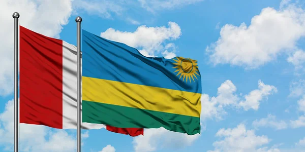 Bandera de Perú y Ruanda ondeando en el viento contra el cielo azul nublado blanco juntos. Concepto diplomático, relaciones internacionales . — Foto de Stock