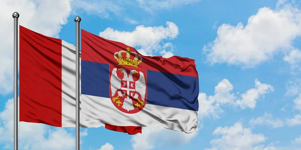 Bandera de Perú y Serbia ondeando en el viento contra el cielo azul nublado blanco juntos. Concepto diplomático, relaciones internacionales . — Foto de Stock