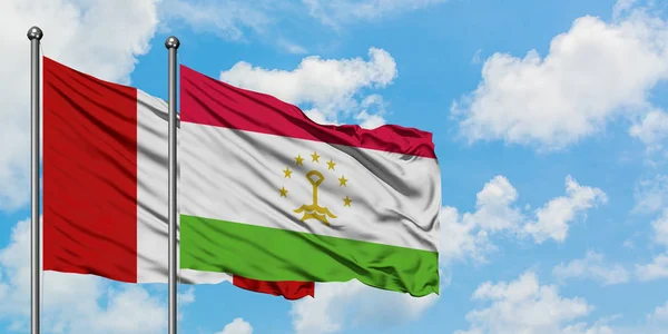 Bandera de Perú y Tayikistán ondeando en el viento contra el cielo azul nublado blanco juntos. Concepto diplomático, relaciones internacionales . — Foto de Stock