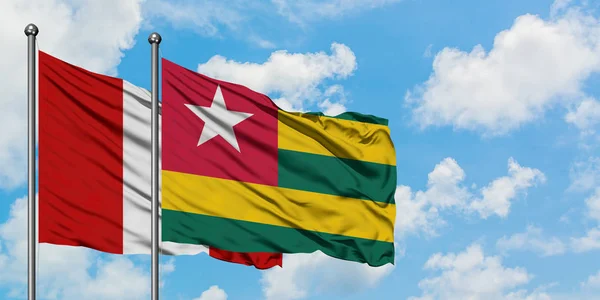Bandera de Perú y Togo ondeando en el viento contra el cielo azul nublado blanco juntos. Concepto diplomático, relaciones internacionales . — Foto de Stock