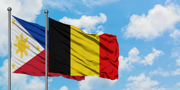 Filipijnen en België vlag zwaaien in de wind tegen witte bewolkte blauwe hemel samen. Diplomatie concept, internationale betrekkingen. — Stockfoto