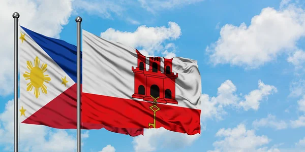 Filipinas e Gibraltar acenando ao vento contra o céu azul nublado branco juntos. Conceito de diplomacia, relações internacionais . — Fotografia de Stock
