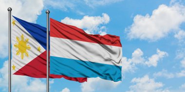 Filipinler ve Lüksemburg bayrağı birlikte beyaz bulutlu mavi gökyüzüne karşı rüzgarsal sallayarak. Diplomasi kavramı, uluslararası ilişkiler.