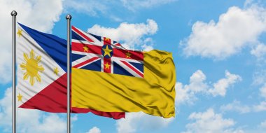 Filipinler ve Niue bayrağı birlikte beyaz bulutlu mavi gökyüzüne karşı rüzgarda sallayarak. Diplomasi kavramı, uluslararası ilişkiler.