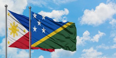 Filipinler ve Solomon Adaları bayrağı birlikte beyaz bulutlu mavi gökyüzüne karşı rüzgarsal sallayarak. Diplomasi kavramı, uluslararası ilişkiler.