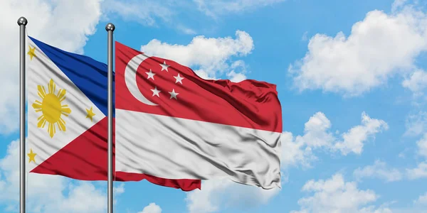 Filipinas e Singapura acenando ao vento contra o céu azul nublado branco juntos. Conceito de diplomacia, relações internacionais . — Fotografia de Stock