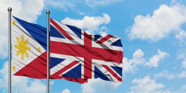 Filipinler ve Birleşik Krallık bayrağı birlikte beyaz bulutlu mavi gökyüzüne karşı rüzgarsal sallayarak. Diplomasi kavramı, uluslararası ilişkiler.