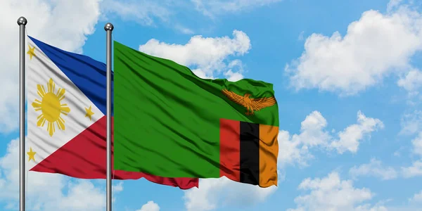 Bandera de Filipinas y Zambia ondeando en el viento contra el cielo azul nublado blanco juntos. Concepto diplomático, relaciones internacionales . — Foto de Stock