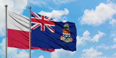 Polonya ve Cayman Adaları bayrağı birlikte beyaz bulutlu mavi gökyüzüne karşı rüzgarda sallayarak. Diplomasi kavramı, uluslararası ilişkiler.