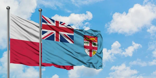 Bandera de Polonia y Fiyi ondeando en el viento contra el cielo azul nublado blanco juntos. Concepto diplomático, relaciones internacionales . — Foto de Stock