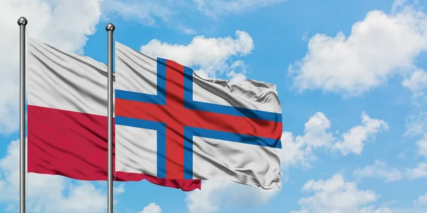 Bandera de Polonia y las Islas Feroe ondeando en el viento contra el cielo azul nublado blanco juntos. Concepto diplomático, relaciones internacionales . — Foto de Stock