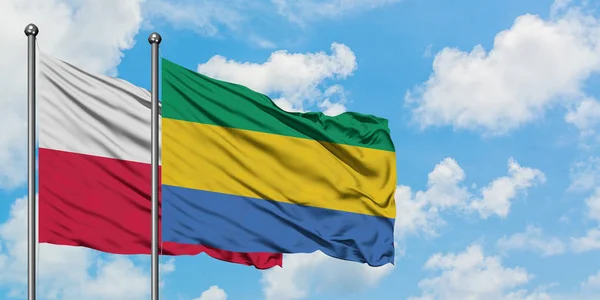 波兰和加蓬国旗在风中飘扬，白云蓝天相聚。外交概念、国际关系. — 图库照片