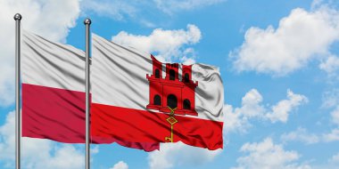 Polonya ve Cebelitarık bayrağı birlikte beyaz bulutlu mavi gökyüzüne karşı rüzgarda sallayarak. Diplomasi kavramı, uluslararası ilişkiler.